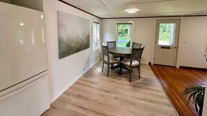 Et spiseområde med et træbord og stole, et hvidt køleskab og et stort abstrakt maleri på væggen.