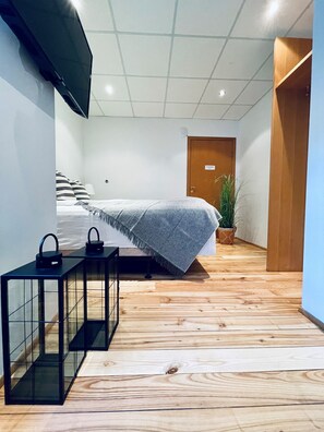 Un dormitorio moderno con una cama, mesitas de noche, un televisor y una planta en maceta.