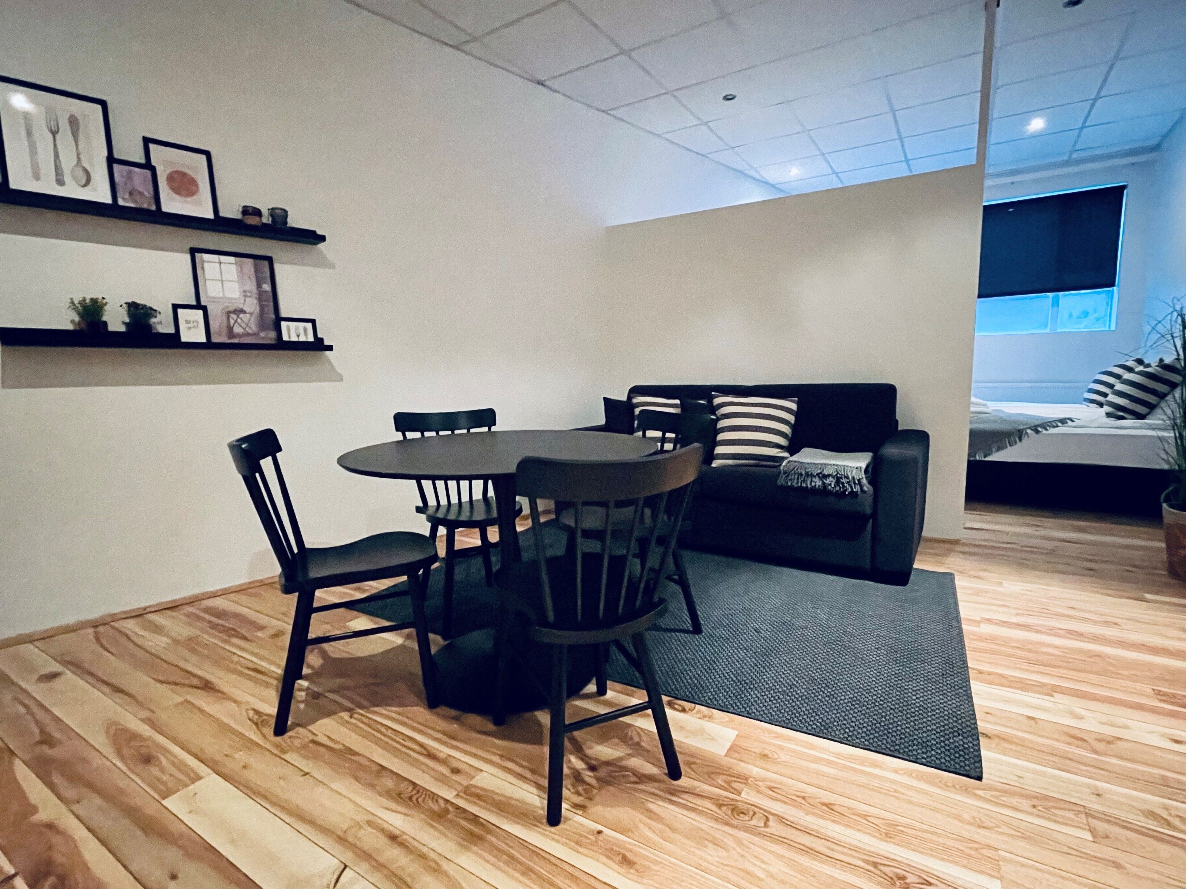 A compact living space with a dining area, a sofa, and a bed.