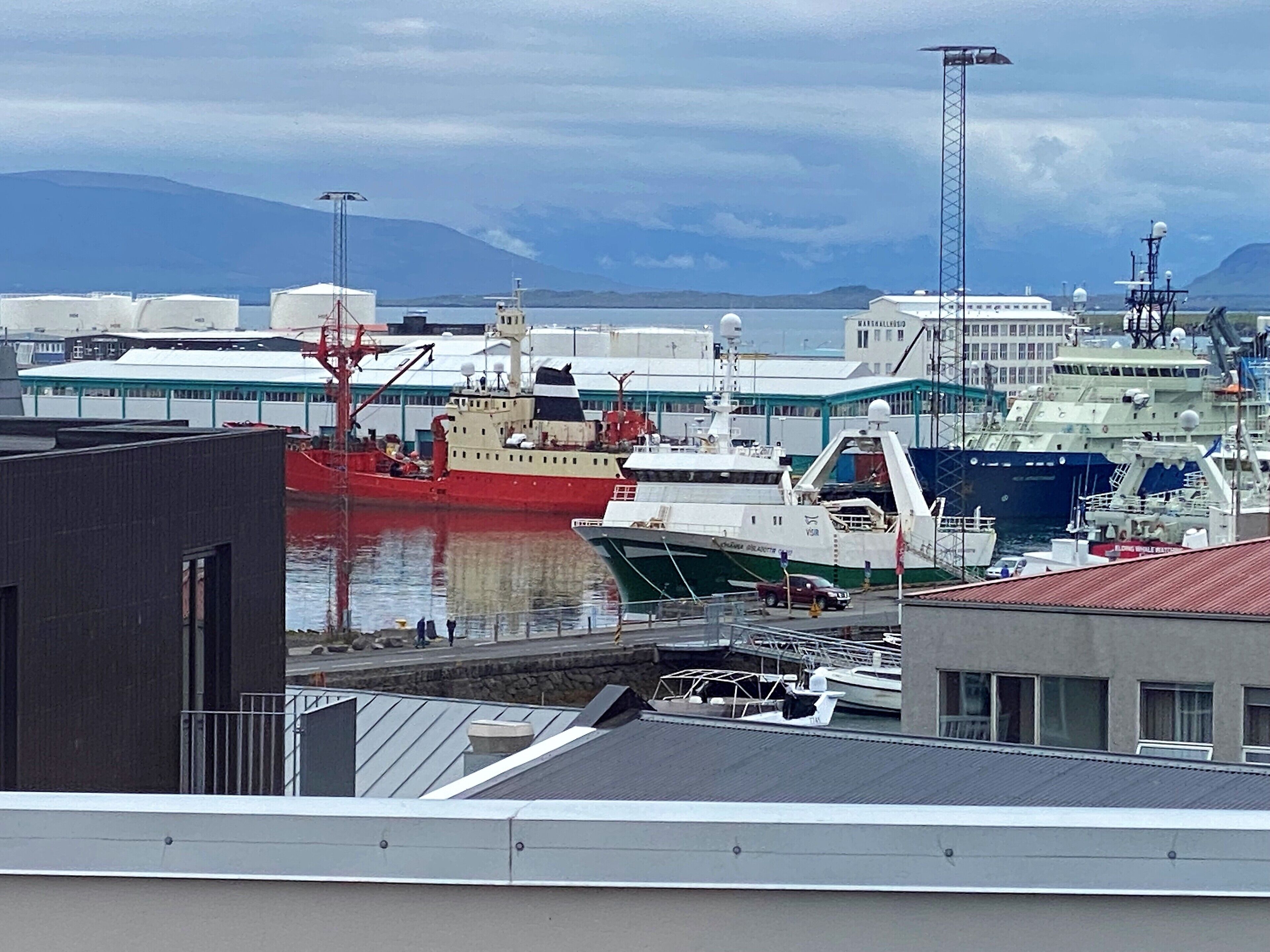 Un port où sont amarrés divers bateaux, dont un navire rouge et un bateau vert.