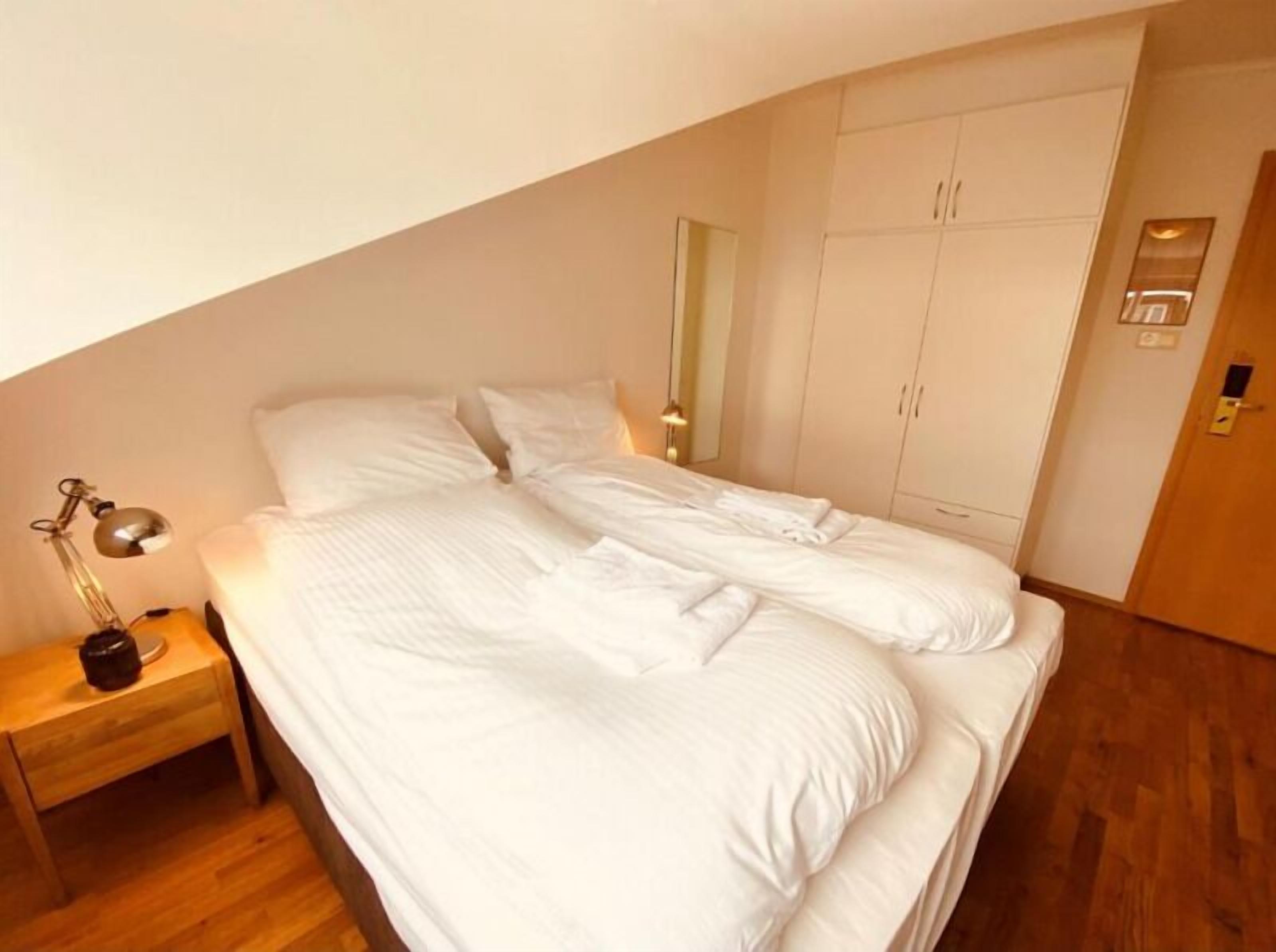 Un dormitorio con cama, mesita de noche, armario y espejo.