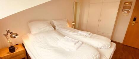 Un dormitorio con cama, mesita de noche, armario y espejo.