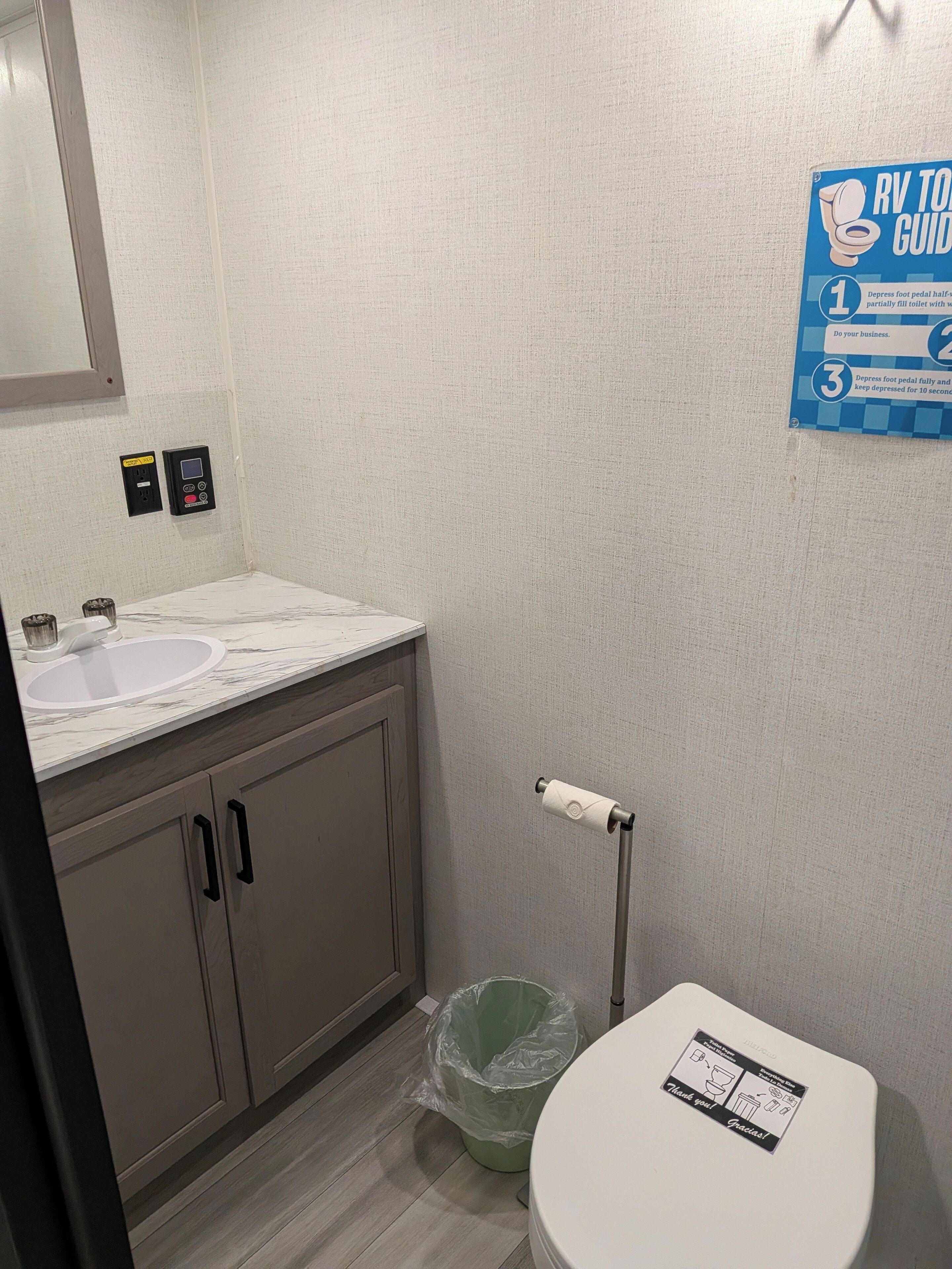 Un bagno con lavandino, WC e asciugatore automatico. Un cartello a parete riporta delle istruzioni.
