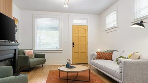Una sala de estar con chimenea, dos sofás, una mesa de centro y una puerta.
