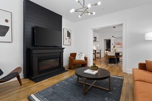 Un salon moderne doté d’une cheminée, d’un téléviseur à écran plat et d’un coin repas avec une table et des chaises.