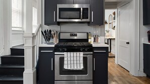 Une cuisine avec des meubles de couleur sombre, un four à micro-ondes en acier inoxydable et une cuisinière.
