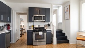Une cuisine moderne avec des meubles de couleur sombre, un four à micro-ondes en acier inoxydable et un four traditionnel.