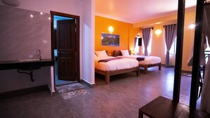A hotel room with two beds, a bathroom with a sink, and a door leading to another room.
