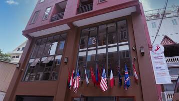 A tall pink building with multiple balconies and flags.