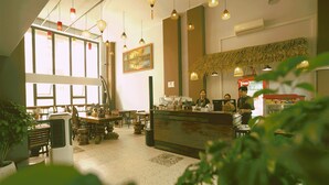 A restaurant with a counter, hanging lights, and a large window.