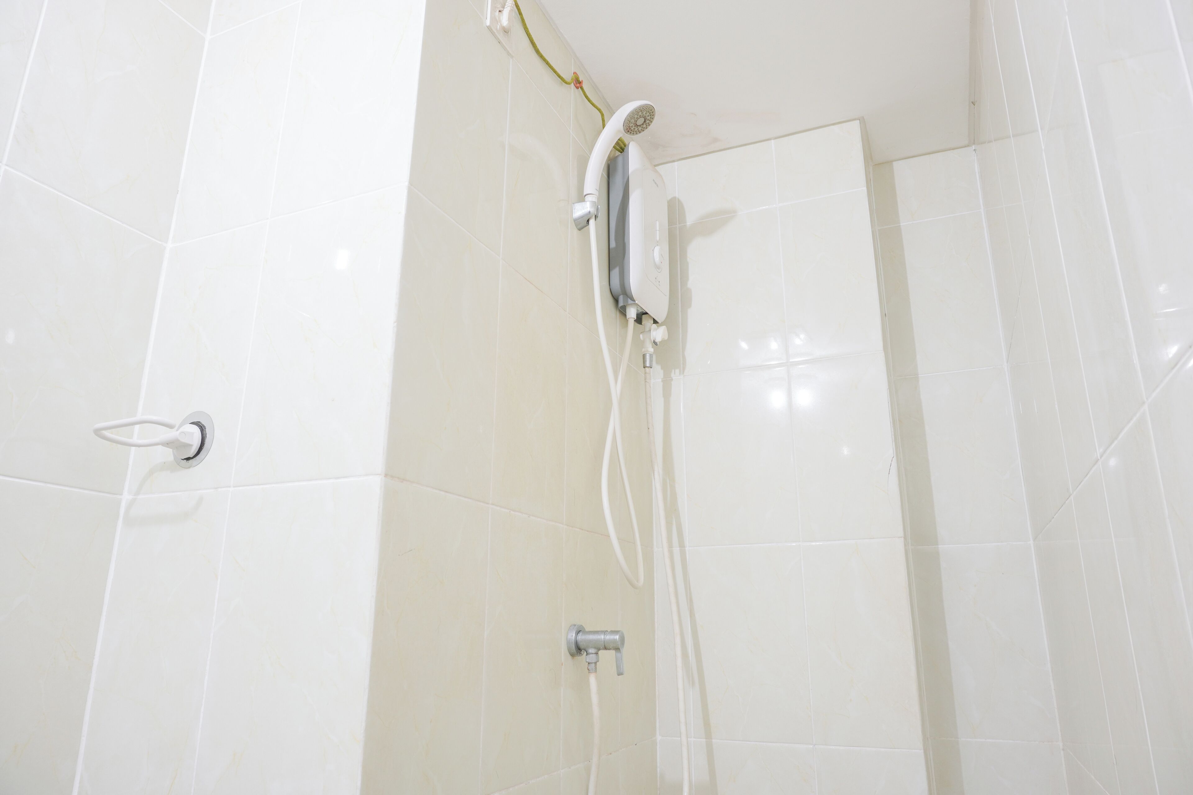 A shower with a handheld showerhead and a wall-mounted faucet.