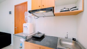Een kleine keuken met een koelkast, een koffiezetapparaat, een magnetron, een broodrooster, een spoelbak en houten kastjes.
