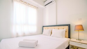 Een hotelkamer met een bed, nachtkastje, lamp en raam met gordijnen.