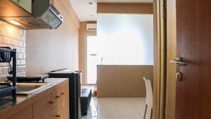 A kitchen with a stove, sink, and cabinets. There is a window with blinds and a door leading to another room. - Modern And Nice Studio At Titanium Square Apartment (Jakarta)