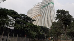 A high-rise building with multiple floors, surrounded by trees and a no parking sign. - Elegant Studio Apartment At High Floor B Residence (Pagedangan)