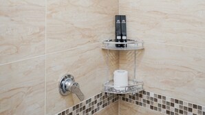 A shower area with a handheld showerhead, a towel rack, and a small shelf with toiletries. - Elegant Studio Apartment At High Floor B Residence (Pagedangan)