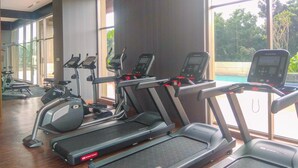 Une salle de sport équipée de tapis de course, de vélos elliptiques et d’un appareil d’aviron.