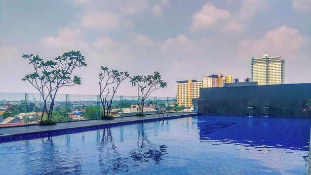 A rooftop swimming pool with a view of a cityscape. - Comfy Studio At Evenciio Margonda Apartment (Depok)