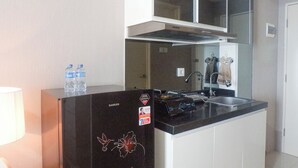 A compact kitchen with a black refrigerator, a sink, and a stove. There are two water bottles on the refrigerator.