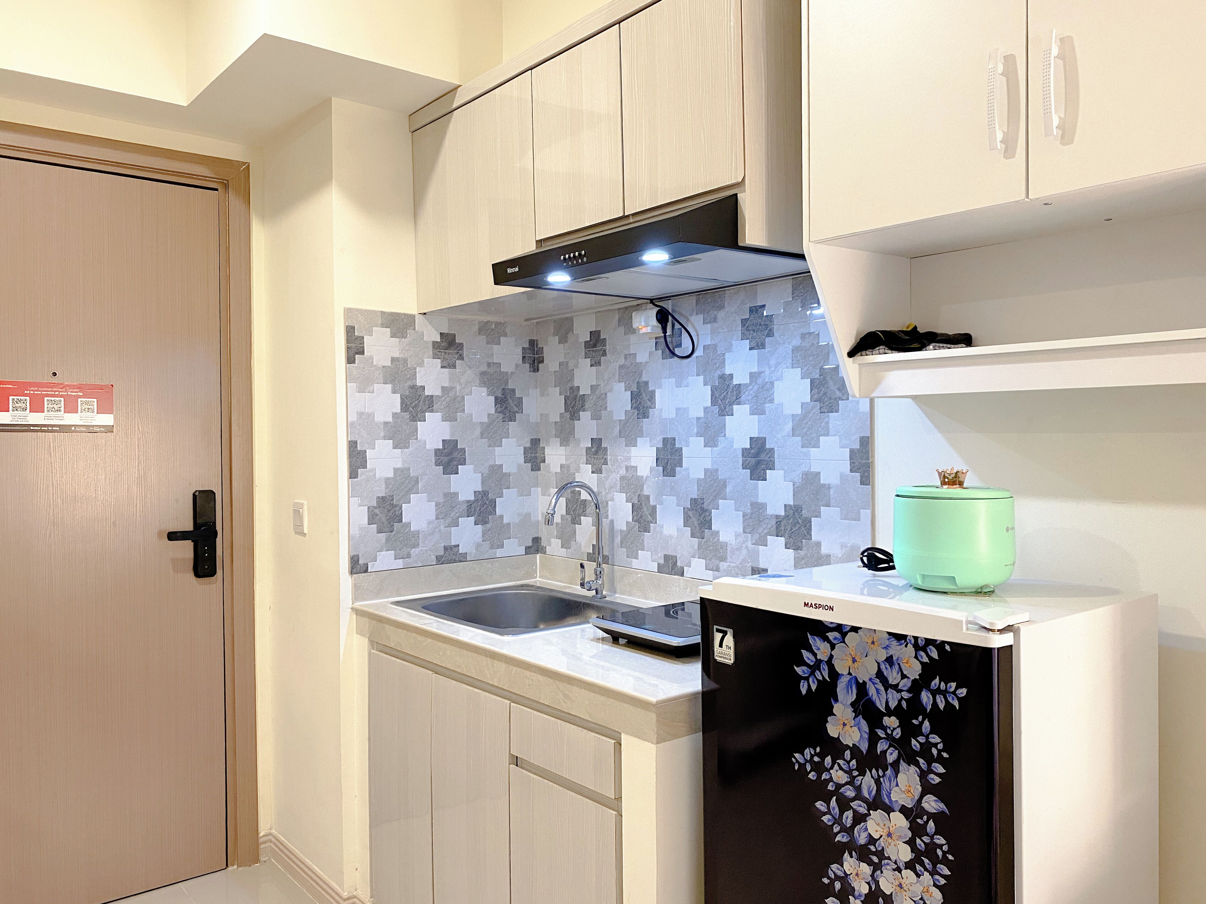 A compact kitchen with a sink, a microwave, and a cabinet with a floral design.