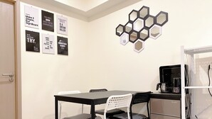 A small dining area with a table and chairs, a coffee machine, and motivational posters on the wall. - Homey 2Br At Meikarta Apartment (Cikarang)