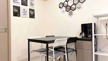 A small dining area with a table and chairs, a coffee machine, and motivational posters on the wall.