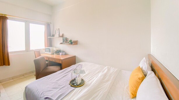 A hotel room with a bed, a desk with a computer, and a window with curtains.