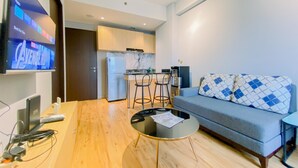 A modern living room with a sofa, a coffee table, and a TV mounted on the wall. - Modern Look 2Br At Transpark Cibubur Apartment (Depok)