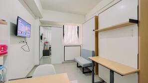Cozy retreat with a flat-screen TV, desk, and bench, perfect for relaxation and productivity.