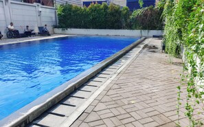 Guests can enjoy a refreshing swim in the pool surrounded by a paved walkway and lush greenery.