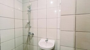 A bathroom with white tiled walls and a white pedestal sink. - Modern Look Studio (No Kitchen) Apartment Bandaraya - Tallasa City Makassar (Makassar)