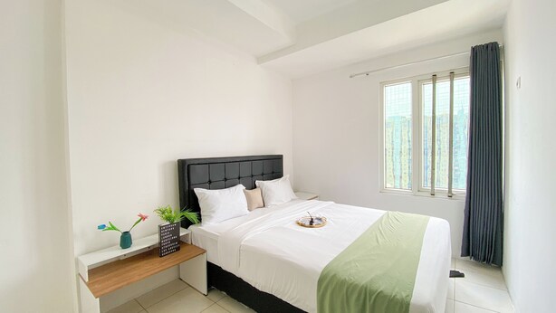 A neatly arranged bedroom with a bed, bedside table, and a window with curtains.