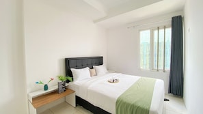 A neatly arranged bedroom with a bed, bedside table, and a window with curtains.