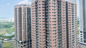 A high-rise residential building with multiple balconies and a view of a river and greenery below. - Simple 2BR at Meikarta Apartment (Cikarang)