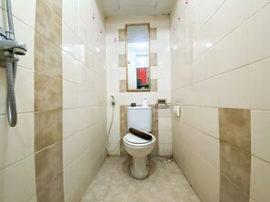 Un baño pequeño y estrecho con inodoro, ducha y espejo.