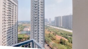A high-rise building with multiple floors and balconies, surrounded by other tall buildings and a highway in the background. - Comfy And Well Furnished Studio Casa De Parco Apartment (Pagedangan)