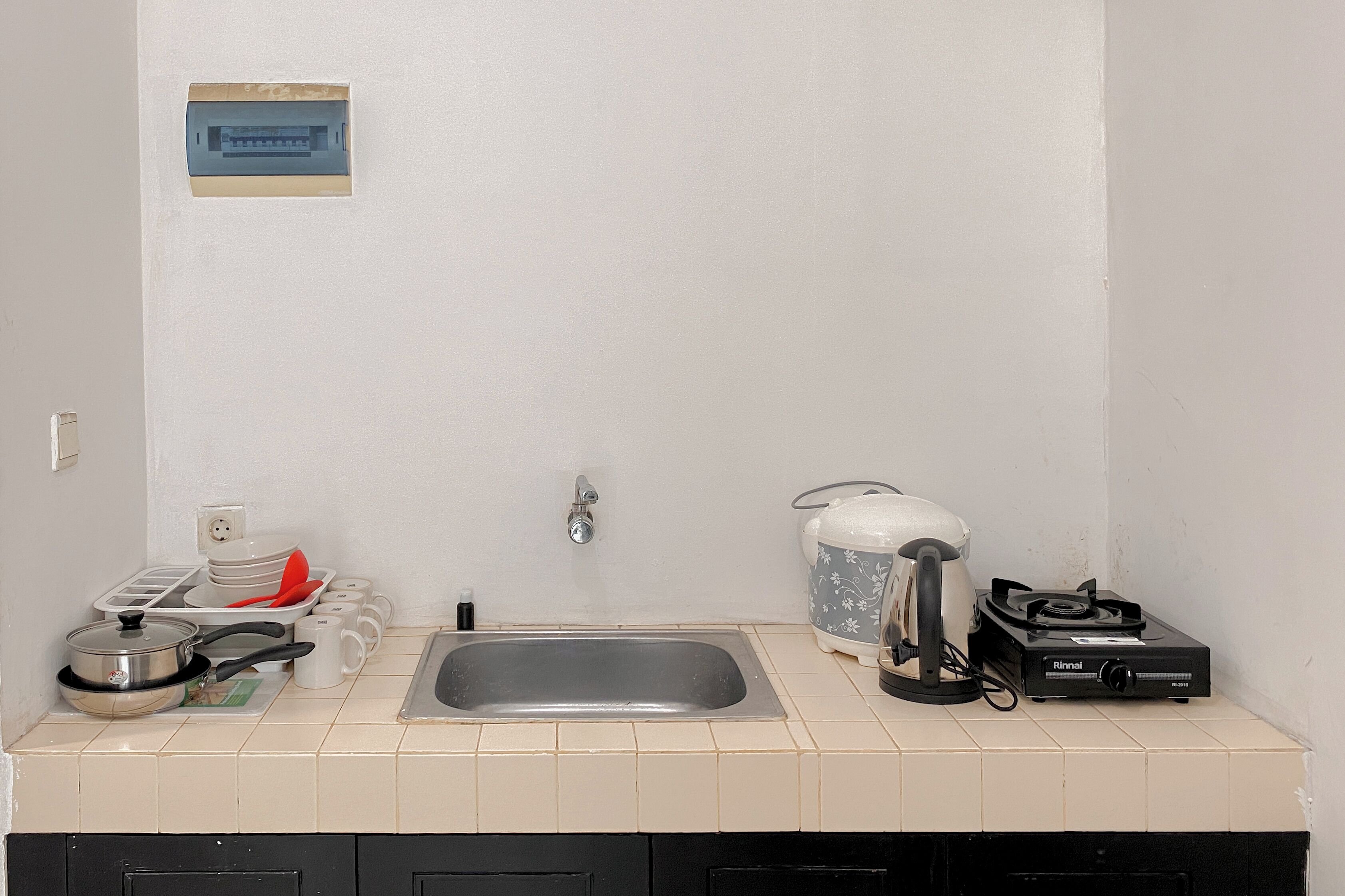 Een keuken met een spoelbak, fornuis en verschillende keukengerei.