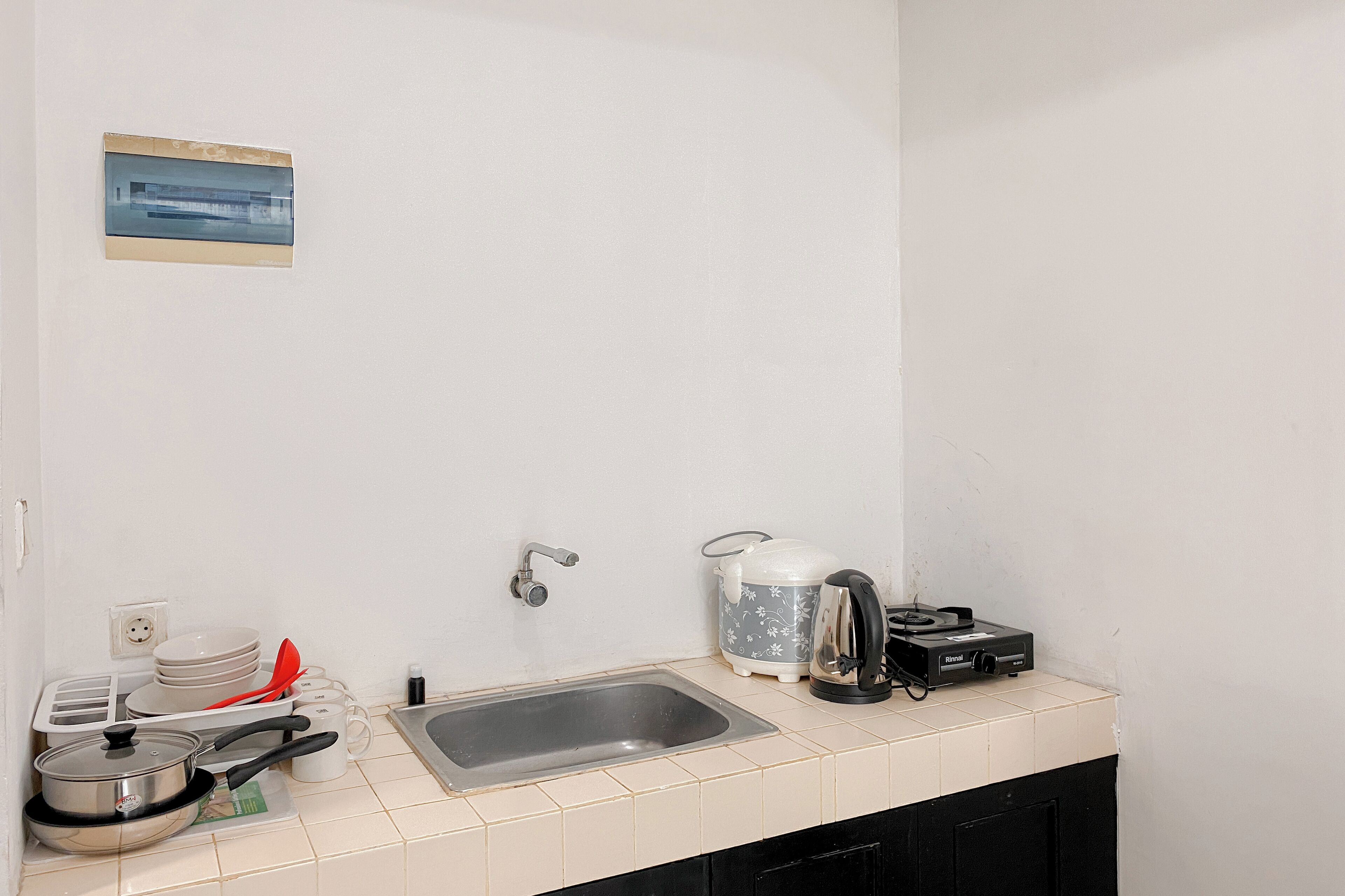 A kitchen with a sink, stove, and various utensils.