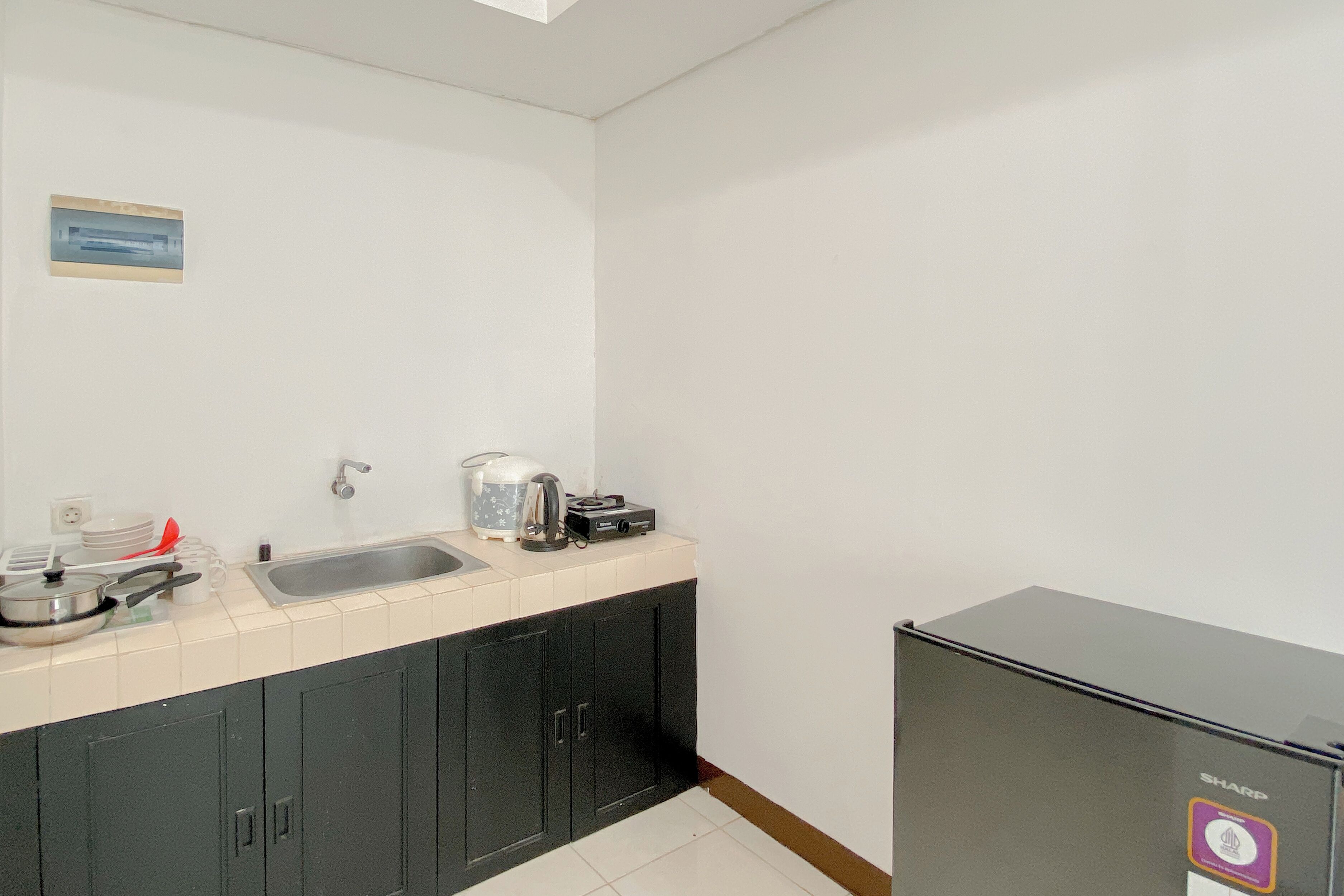 A small kitchenette with a sink, a kettle, a coffee maker, and a black cabinet.