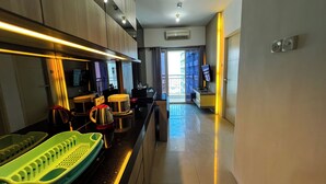 A modern kitchen with a long countertop, a coffee maker, a kettle, and a sink.