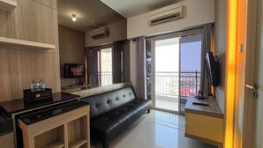 A modern living room with a sofa, a TV, a wooden table, and a balcony with a view.