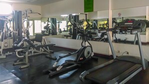 Ein Fitnessstudio mit verschiedenen Trainingsgeräten, darunter Laufbänder, Crosstrainer und Kraftgeräte.