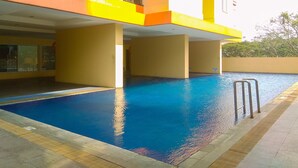 A swimming pool area with a clear blue pool, a 1.2m depth marker, and a safety ladder.