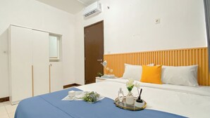 Een hotelkamer met een bed, nachtkastje, raam en deur.