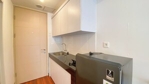 Une cuisine compacte dotée d’un réfrigérateur encastré, d’un évier et d’un petit plan de travail.