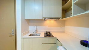 A compact kitchen with a sink, stove, and upper cabinets. - Modern And Cozy Living 1Br At Gold Coast Apartment (Jakarta)
