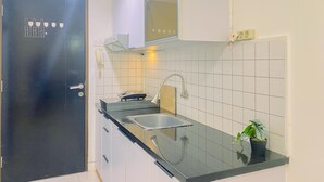 Eine moderne Küche mit weißen Schränken, einer schwarzen Arbeitsplatte, einem Spülbecken und einem Blumentopf.