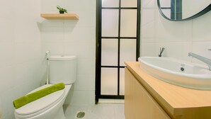 Ein Badezimmer mit Toilette, Waschbecken, Spiegel und einer Tür mit schwarzem Rahmen.