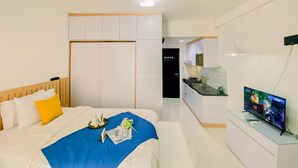 Ein Hotelzimmer mit Bett, Fernseher, Küchenzeile und Bad.
