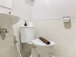 A bathroom with a toilet, a sink, and a toilet paper holder. - Good And Warm Studio At Transpark Juanda Bekasi Timur Apartment (Bekasi)
